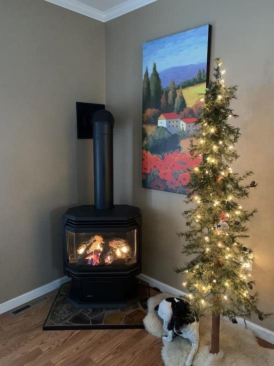 small Christmas tree decorated with ornaments and lights sits next to a fireplace